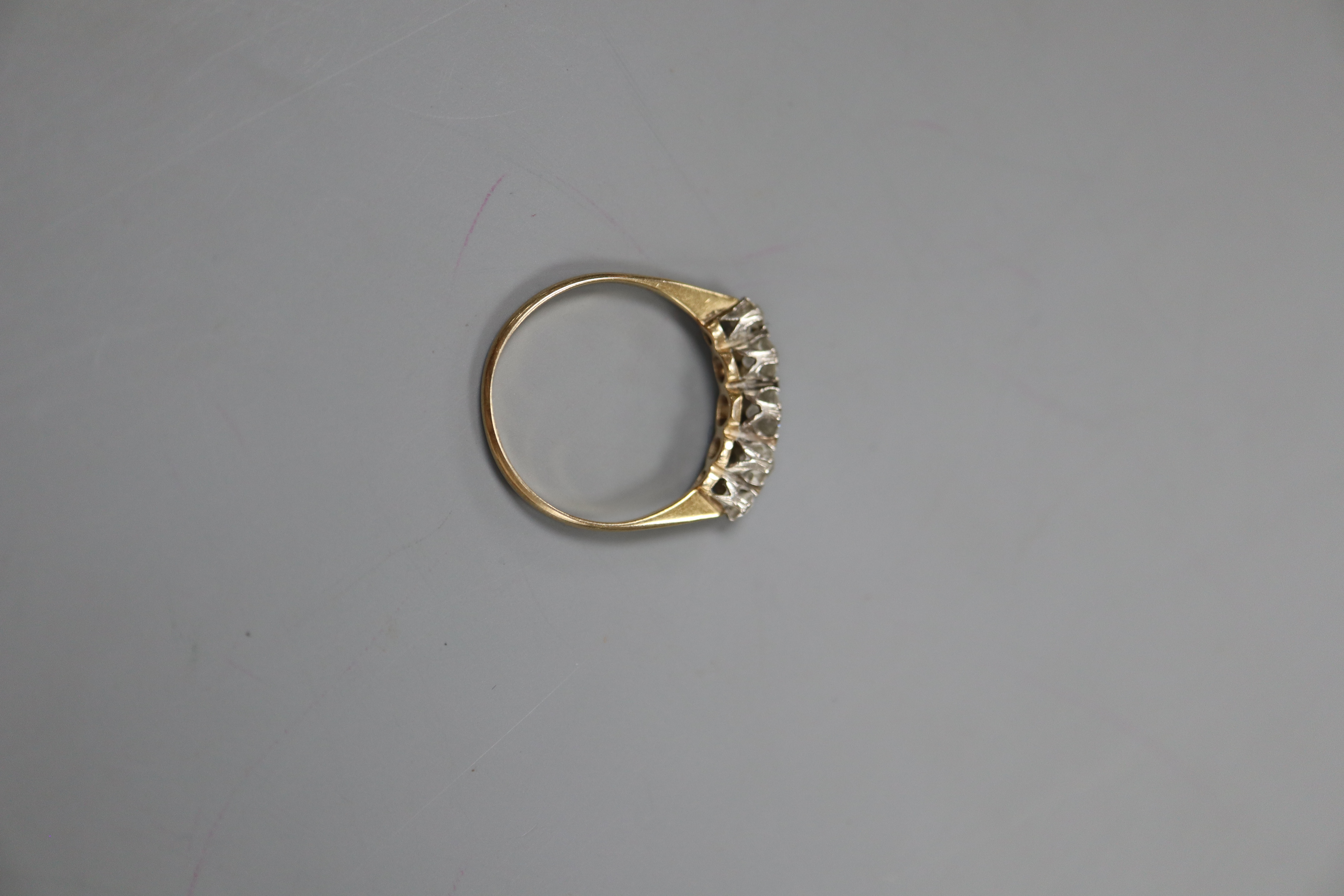 A yellow metal and graduated five stone diamond set half hoop ring, size O, gross 2.1 grams.